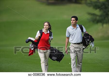 Side view of a couple walking on the fairway as they carry their golf bags View Large Photo Image Stock Photograph - Side view of a couple walking on the fairway as they carry their golf bags. Fotosearch