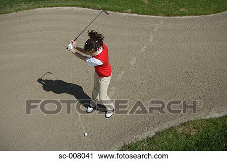 Stock Image - Woman playing a bunker shot. Fotosearch