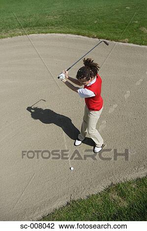 Stock Image - Woman playing a bunker shot. Fotosearch