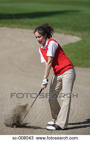 Stock Image - Woman playing a bunker shot. Fotosearch