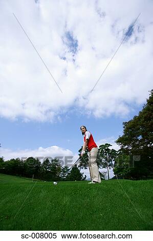 Stock Photography - Young woman contemplating before playing a golf shot. Fotosearch