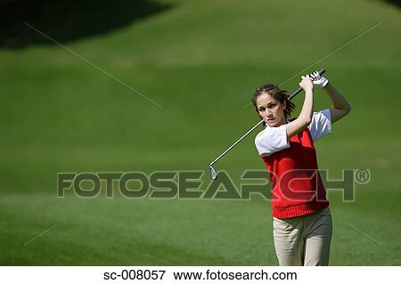 Stock Photo - Young woman making a stroke with a golf club. Fotosearch