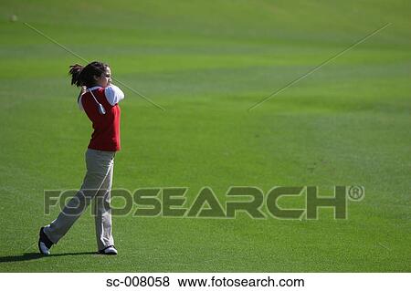 Stock Photo - Young woman making a stroke with a golf club. Fotosearch