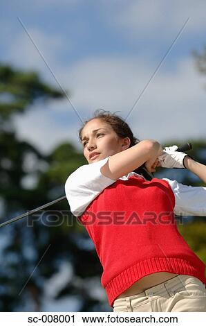 Stock Image - Young woman playing golf. Fotosearch