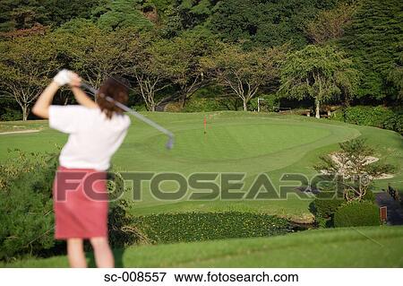 Stock Photo - Young Woman Plays Golf Against a Landscape. Fotosearch