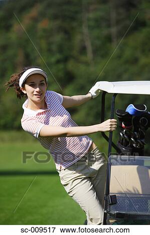 A woman stretching as she holds onto a golf cart View Large Photo Image Stock Photo - A woman stretching as she holds onto a golf cart. Fotosearch