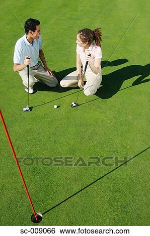 Couple smiling at each other on the green View Large Photo Image Stock Photograph - Couple smiling at each other on the green. Fotosearch