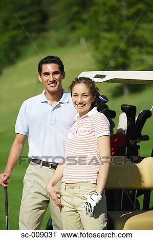 Couple standing near a golf cart View Large Photo Image Stock Image - Couple standing near a golf cart. Fotosearch