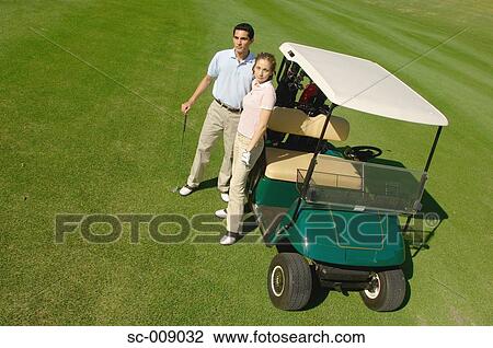 Stock Image - Couple standing near a golf cart. Fotosearch