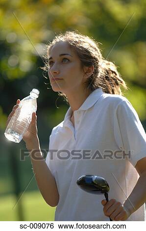 Stock Photograph - Female golfer taking a drink break. Fotosearch