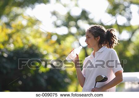 Stock Photography - Female golfer taking a drink break. Fotosearch