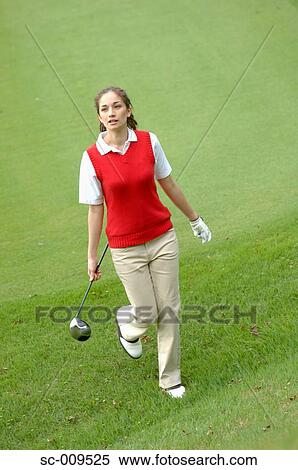 Stock Photography - Female golfer walking down the fairway with ball and club. Fotosearch