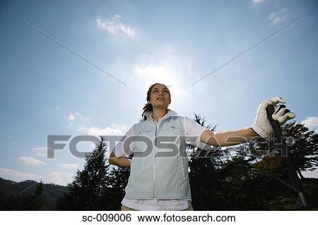 Stock Photograph - Low angle view of a female golfer on a sunny day. Fotosearch