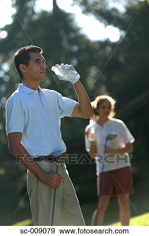 Male golfer drinking whilst he contemplates his next shot View Large Photo Image Stock Photo - Male golfer drinking whilst he contemplates his next shot. Fotosearch