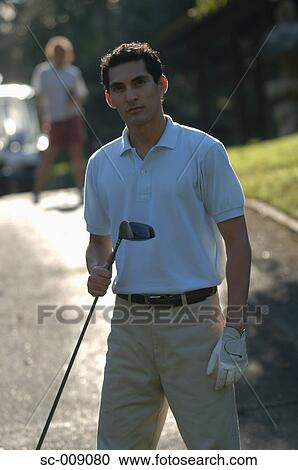 Stock Image - Male golfer posing while holding a club. Fotosearch