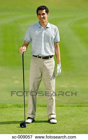 Stock Photo - Man posing in front of the camera holding a golf club. Fotosearch