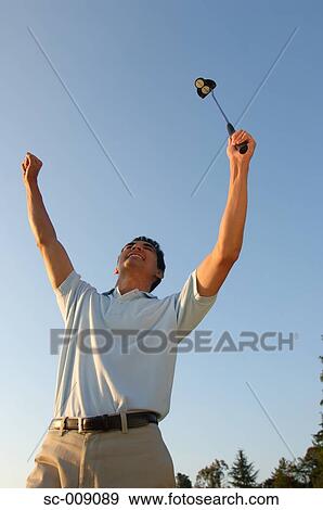 Stock Photo - Man raising his hands in excitement after making a winning putt. Fotosearch