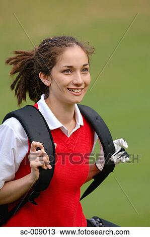 Stock Image - Portrait of a woman carrying a golf bag. Fotosearch