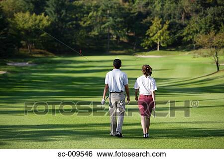 Stock Photograph - Rear view of a couple walking down the fairway. Fotosearch