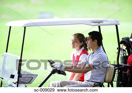 Stock Photo - Side view of a couple in a golf cart. Fotosearch