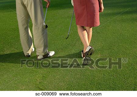 Stock Photo - Waist down view of a couple holding golf clubs. Fotosearch