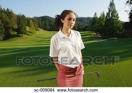 Woman facing the camera with a golf course stretching behind View Large Photo Image Picture - Woman facing the camera with a golf course stretching behind. Fotosearch
