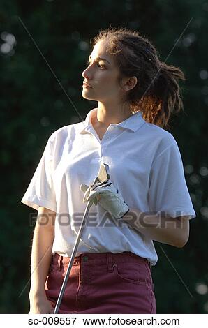Stock Photo - Woman facing the sun and holding a golf club in her hand. Fotosearch
