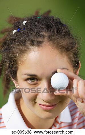 Stock Photo - Woman Holds a Golf Ball in Front of Her Eye. Fotosearch