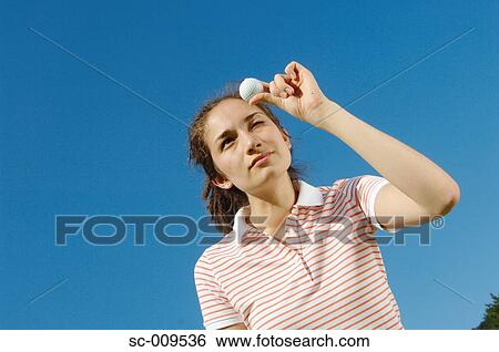 Woman looks at a golf ball View Large Photo Image Stock Photograph - Woman looks at a golf ball. Fotosearch