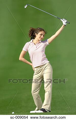 Picture - Woman posing in front of the camera holding a golf club. Fotosearch