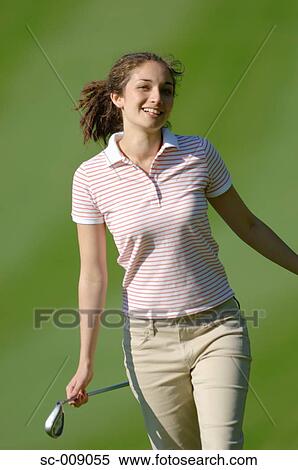 Woman posing in front of the camera holding a golf club View Large Photo Image Stock Photography - Woman posing in front of the camera holding a golf club. Fotosearch