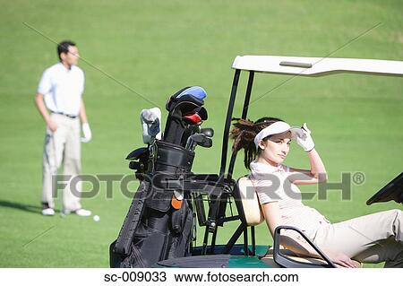 Stock Image - Woman relaxing on a golf cart. Fotosearch