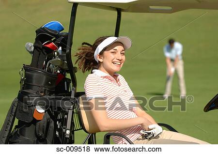 Stock Photo - Woman smiling at the camera from her golf cart. Fotosearch