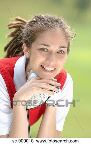 Stock Photo - Woman smiling at the camera holding a golf club. Fotosearch