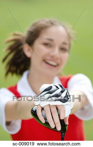 Stock Photo - Woman smiling at the camera holding a golf club. Fotosearch