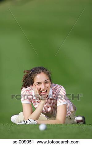 Stock Image - Woman smiling at the camera while resting on the golf course. Fotosearch