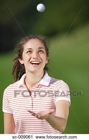 Stock Image - Young Golfer Tossing a Golf Ball. Fotosearch
