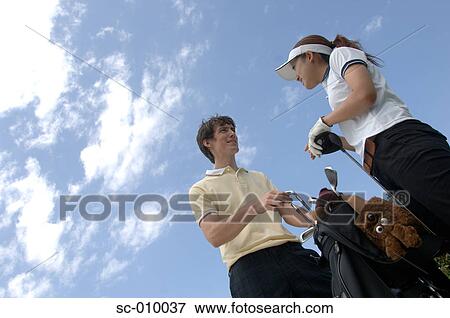Stock Photo - A man and a woman converses over a golf bag. Fotosearch