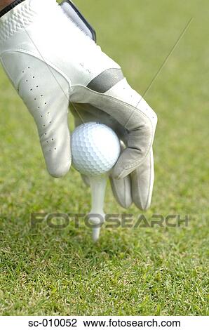 Stock Image - Close up of a mans hand teeing a golf ball. Fotosearch