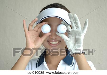 Close up of a woman holding two golf balls in front of her eyes View Large Photo Image Stock Photography - Close up of a woman holding two golf balls in front of her eyes. Fotosearch