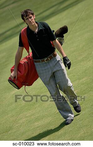 Stock Image - Front view of a man carrying a red colored golf bag. Fotosearch