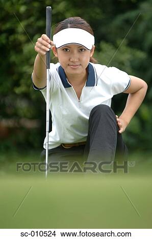 Front view of a woman holding a golf club View Large Photo Image Picture - Front view of a woman holding a golf club. Fotosearch
