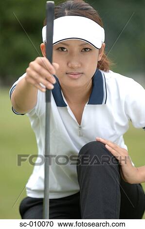 Stock Image - Front view of a woman holding a golf club. Fotosearch