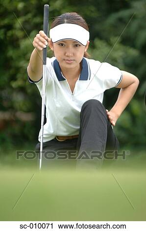 Stock Image - Front view of a woman holding a golf club. Fotosearch