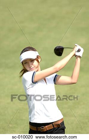 Stock Image - Front view of a woman playing a golf stroke. Fotosearch