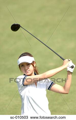 Stock Image - Front view of a woman playing a golf stroke. Fotosearch