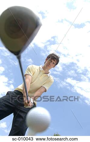 Stock Image - Low angle view of a man playing a golf shot. Fotosearch