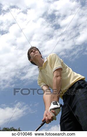 Stock Photograph - Low angle view of a man playing a golf shot. Fotosearch