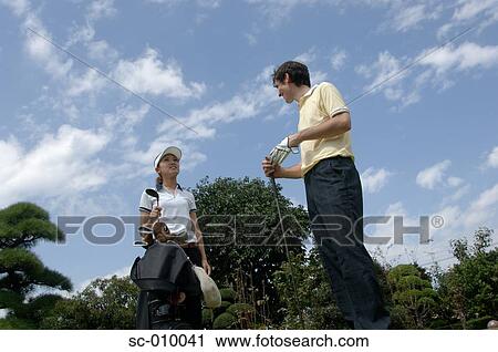 Stock Image - Man and a woman chatting on a the tee ground. Fotosearch
