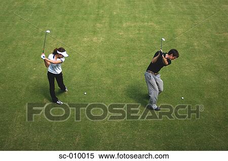 Stock Photography - Man and a woman playing simultaneous golf strokes. Fotosearch